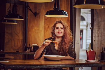 Young redhead female eating spicy noodles in an Asian restaurant.