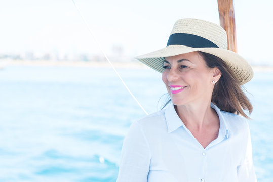 Beautiful middle age woman traveling on sailboat and smiling happy and confident.