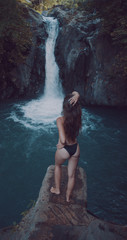 Back view of young beautiful tourist visiting the Aling-Aling waterfall of the Bali island, Indonesia. Having fun in the wild nature. Lifestyle. Travel photography