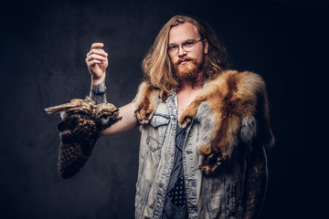 Portrait of a tattoed redhead hipster male with long luxuriant hair and full beard dressed in a...