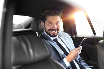 businessman smiling while sitting in the back seat in the car