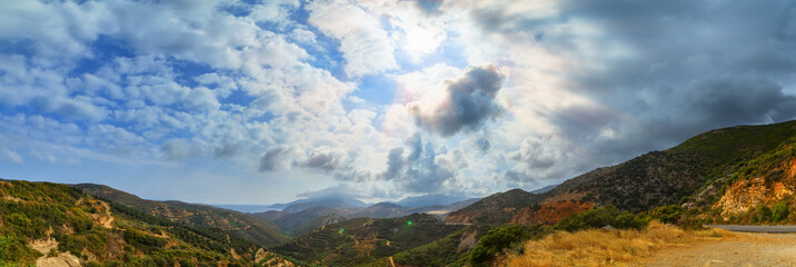 panorama view of the mountains, storm clouds and sun with rays on beach, Crete Greece
