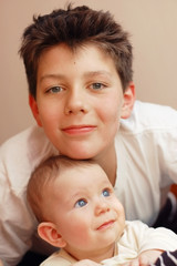 Vertical portrait of two brothers. The elder brother hugs a younger little brother. The little boy looks to the side