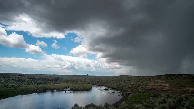Time lapse of summer rainstorm moving across the desert next to river in the Idaho landscape.