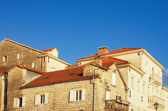 Old houses with red roofs under blue sky. Ancient town of Perast, Montenegro