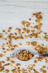 Spoon full of granola on white wood table, top view