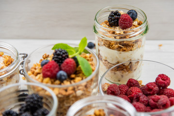 Jars full with granola, yogurt and fresh berries, close-up, selective focus
