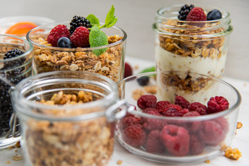 Jars full with granola, yogurt and fresh berries, close-up, selective focus