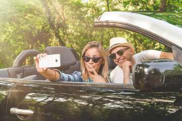 Beautiful couple taking self portrait from their cabriolet car in nature.