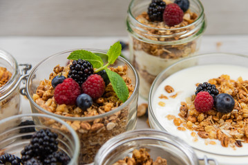 Jars full with granola, yogurt and fresh berries, close-up, selective focus