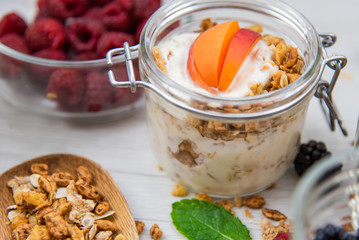 Jars full with granola, yogurt and fresh berries and wood spoon full whit granola, close-up, selective focus