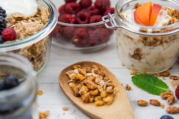 Jars full with granola, yogurt and fresh berries and wood spoon full whit granola, close-up, selective focus