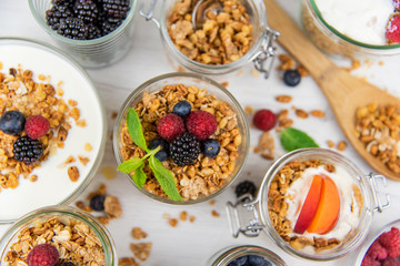 Jars full with granola, yogurt and fresh berries and wood spoon full whit granola, top view, selective focus