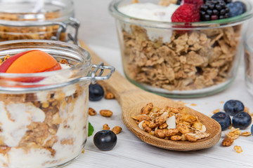 Jars full with granola, yogurt and fresh berries and wood spoon full whit granola, close-up, selective focus