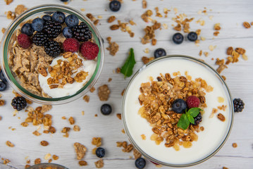 Bowls of yogurt with granola and fresh berries on white wood table, top view