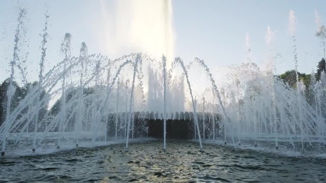 Water fountain in park at sunset. Slow motion.