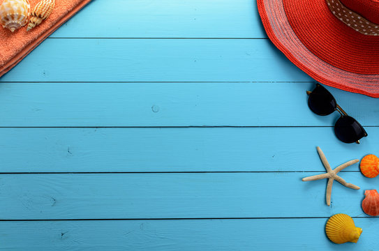 
Summer marine accessories - a hat, sunglasses, shoes, shells and stars on a blue background wooden 