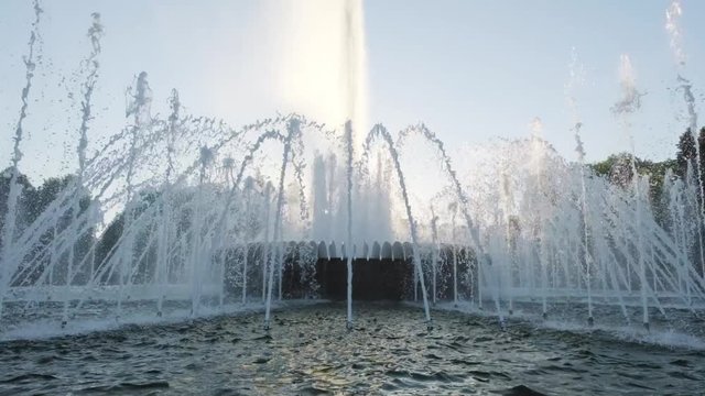 Water fountain in park at sunset. Slow motion.