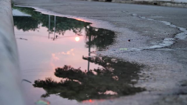 reflection twilight sunset sky in puddle water flooding on street