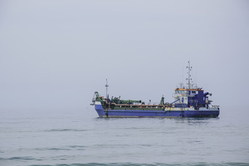 Fototapeta na wymiar Big blue boat at the sea on cloudy day