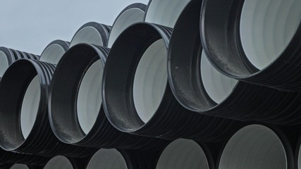 Warehouse of finished plastic pipes industrial outdoors storage site. Manufacture of plastic water pipes factory. Process of making plastic tubes on the machine tool with the use of water and air