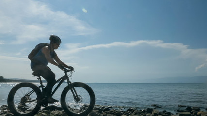 Fototapeta premium Fat bike zwany także fatbike lub fat-tire bike latem podczas jazdy po plaży. Facet idzie prosto na plażę. Po piasku na takim rowerze jazda nie jest trudna.