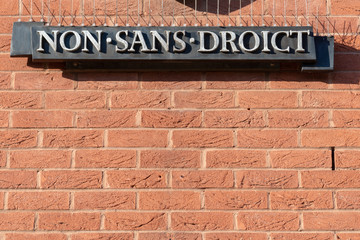sign on brick wall stating non sans droict meaning not without right and the motto of William Shakespeare
