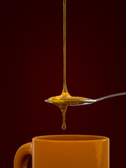 a spoon full of golden honey over a tea mug