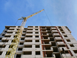 Naklejka premium Concrete building under construction. Industrial crane near building. Construction site.