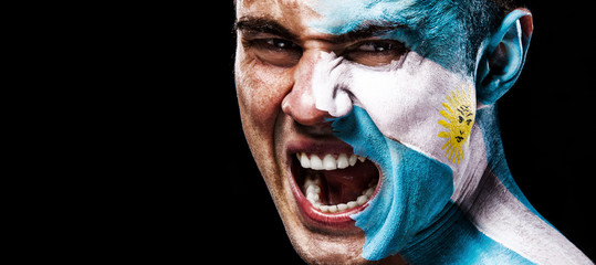 Soccer or football fan with bodyart on face with agression - flag of Argentina.