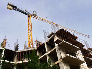 Construction crane near building. Concrete building under construction.