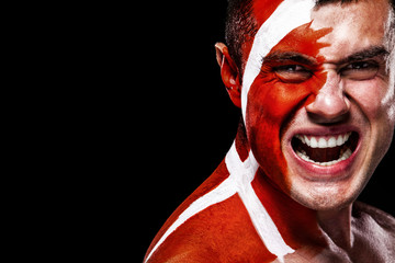 Soccer or football fan with bodyart on face with agression - flag of Denmark.