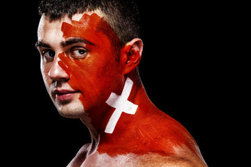 Soccer or football fan with bodyart on face with agression - flag of Switzerland.
