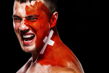 Soccer or football fan with bodyart on face with agression - flag of Switzerland.