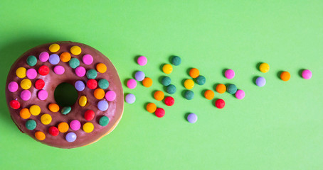 Donut chocolate glaze and sprinkles, top view and isolated, on green background.