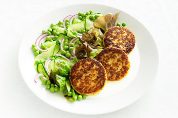 cod cutlets on lettuce leafs served with mayonnaise sauce and salad of peas, cucumber, and onion