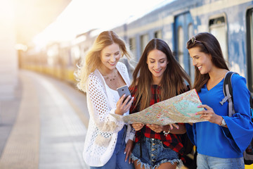 Group of girl friends tourists on railway platform