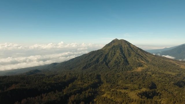 Flight over the mountains in the early morning. Aerial view of Green tropical mountain cover with cloud Banyuwangi Regency of East Java, Indonesia. 4K Aerial footage.