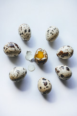 Broken quail egg surrounded by whole eggs on white background, close up. Concept killing, ritual, suicide, sacrifice