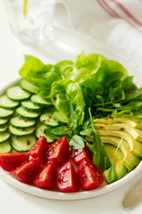 Vegetable salad with avocado and flax seeds on a light background, vegan food.
