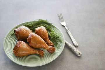 Smoked chicken drumsticks on  green plate.