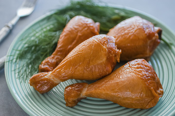 Smoked chicken drumsticks on a green plate.