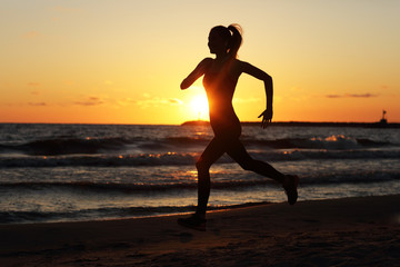 Fototapeta na wymiar Woman running alone at beautiful dusk on the beach