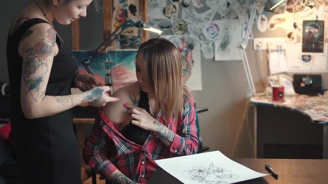 tattoo artist discusses with a client sketch tattoo. tattoo master in home Studio
