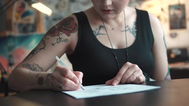 tattoo master makes a sketch of tattoo on paper