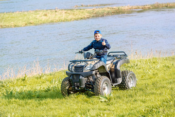 The boy is traveling on an ATV.