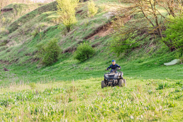 The boy skates on a quad bike in a beautiful area.