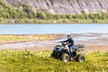 The boy is traveling on an ATV.