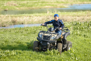The boy is traveling on an ATV.