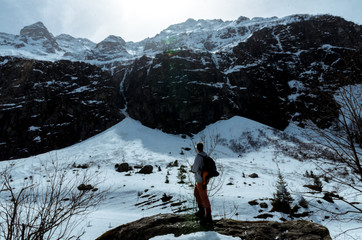 A lone traveler wandering in front of snowy peaks of mountains
